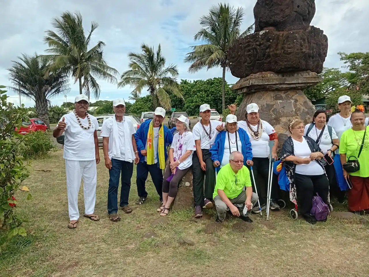 Rapa Nui community group including elderly and disabled members beside a carved moai on Easter Island